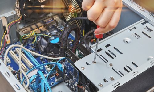 Handyman is untightening a screw of the hard drive of the personal computer, close-up.