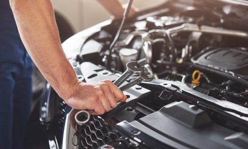 Picture showing muscular car service worker repairing vehicle.
