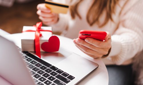Close up of woman hands with mobile phone, credit card, gifts and laptop. Online shopping at Christmas, valentine day or birthday holidays. Freelance girl woking from home office